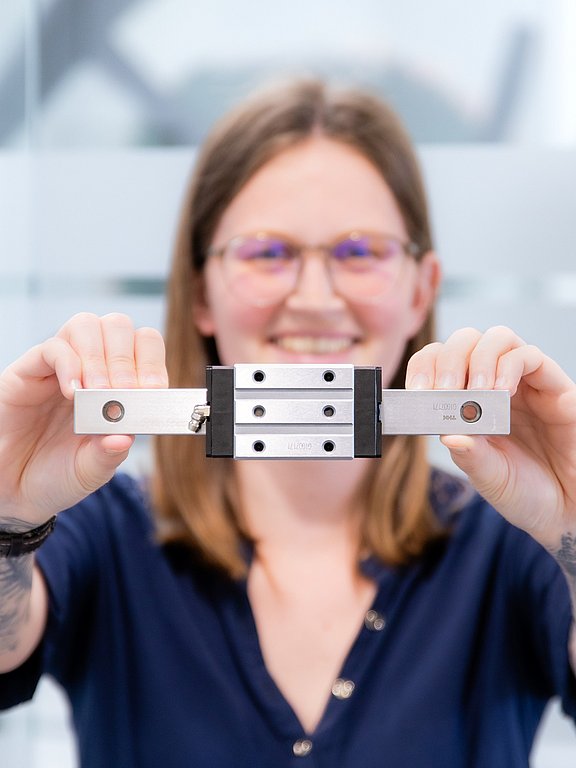 Patrick Fasching, Produktmanager für Lineartechnik bei HENNLICH, hält eine Linearführung in beiden Händen.