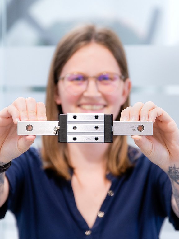 Patrick Fasching, Produktmanager für Lineartechnik bei HENNLICH, hält eine Linearführung in beiden Händen.