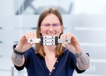 Patrick Fasching, Produktmanager für Lineartechnik bei HENNLICH, hält eine Linearführung in beiden Händen.