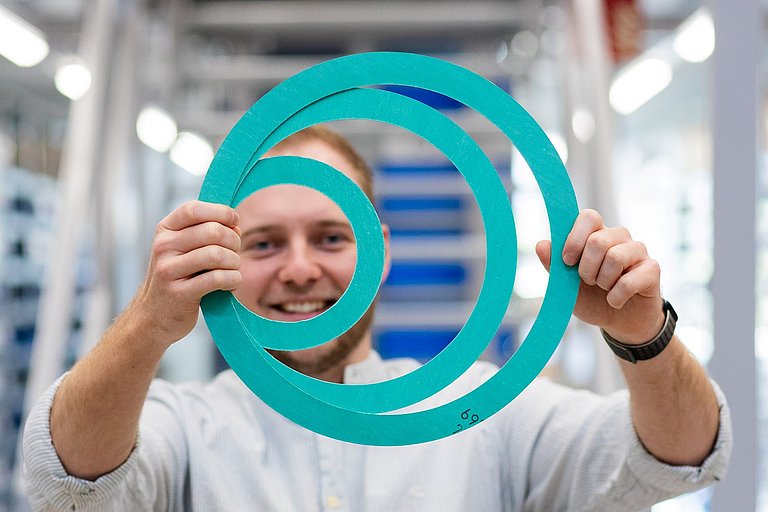 Flachdichtungen_NicoSmuda Nico Smuda, Techniker bei HENNLICH, hält 3 Flachdichtungen in beiden Händen