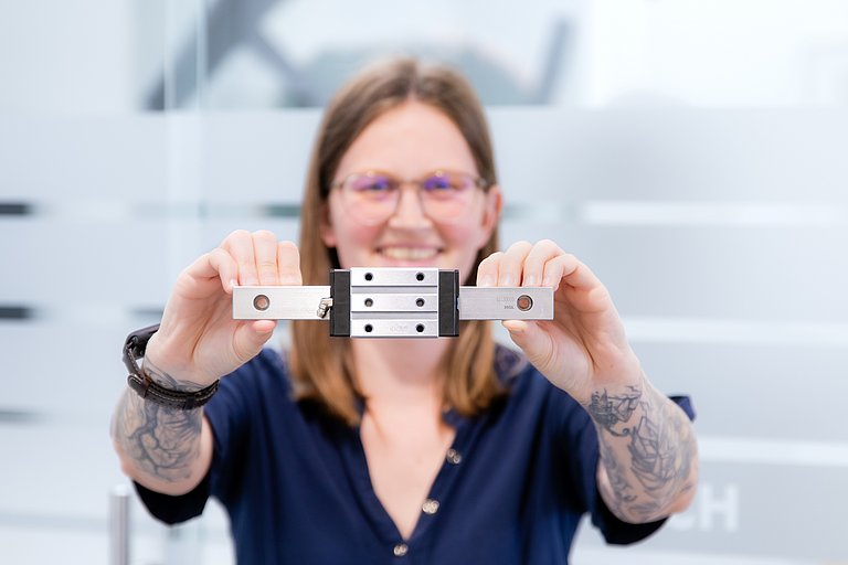 Patrick Fasching, Produktmanager für Lineartechnik bei HENNLICH, hält eine Linearführung in beiden Händen.