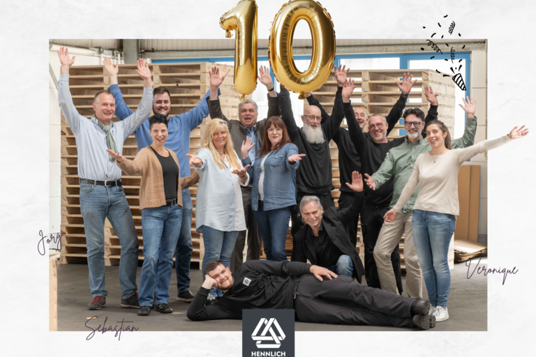 Gruppenbild mit jubelnden Mitarbeitern mit einer 10 aus goldenen Luftballons